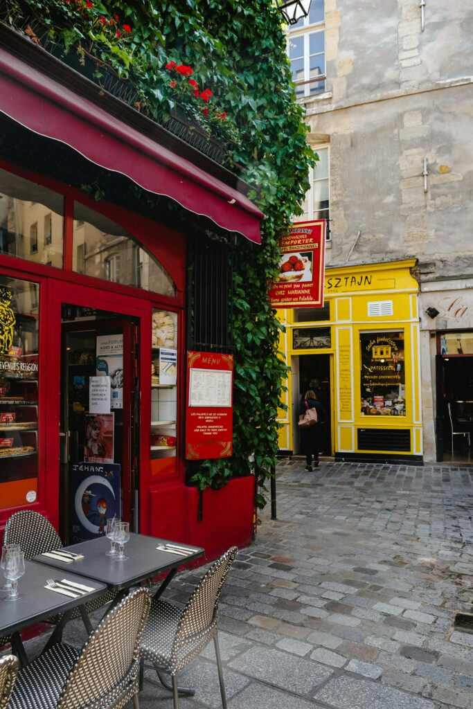 pexels-photo-2574474-2574474 Explore a picturesque Parisian café scene with vibrant colors and ivy-covered walls on a bustling street.